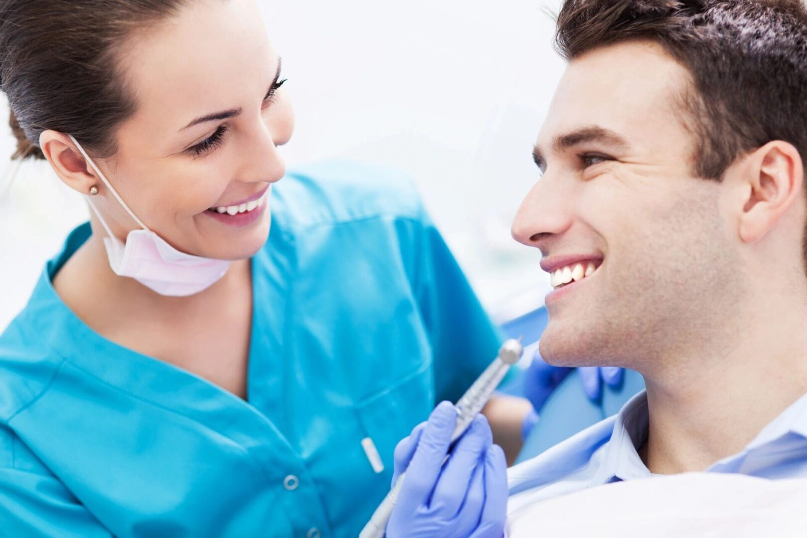 A woman in blue scrubs is holding a tooth brush