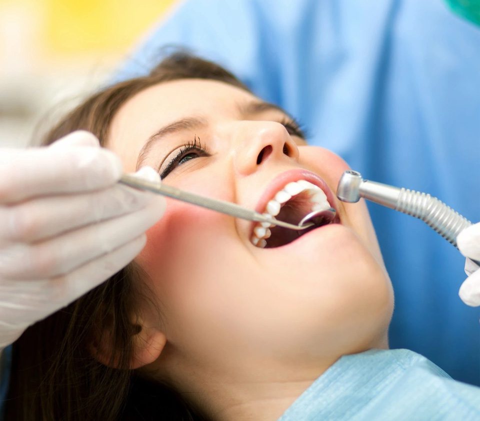 A woman is getting her teeth checked by an dentist.