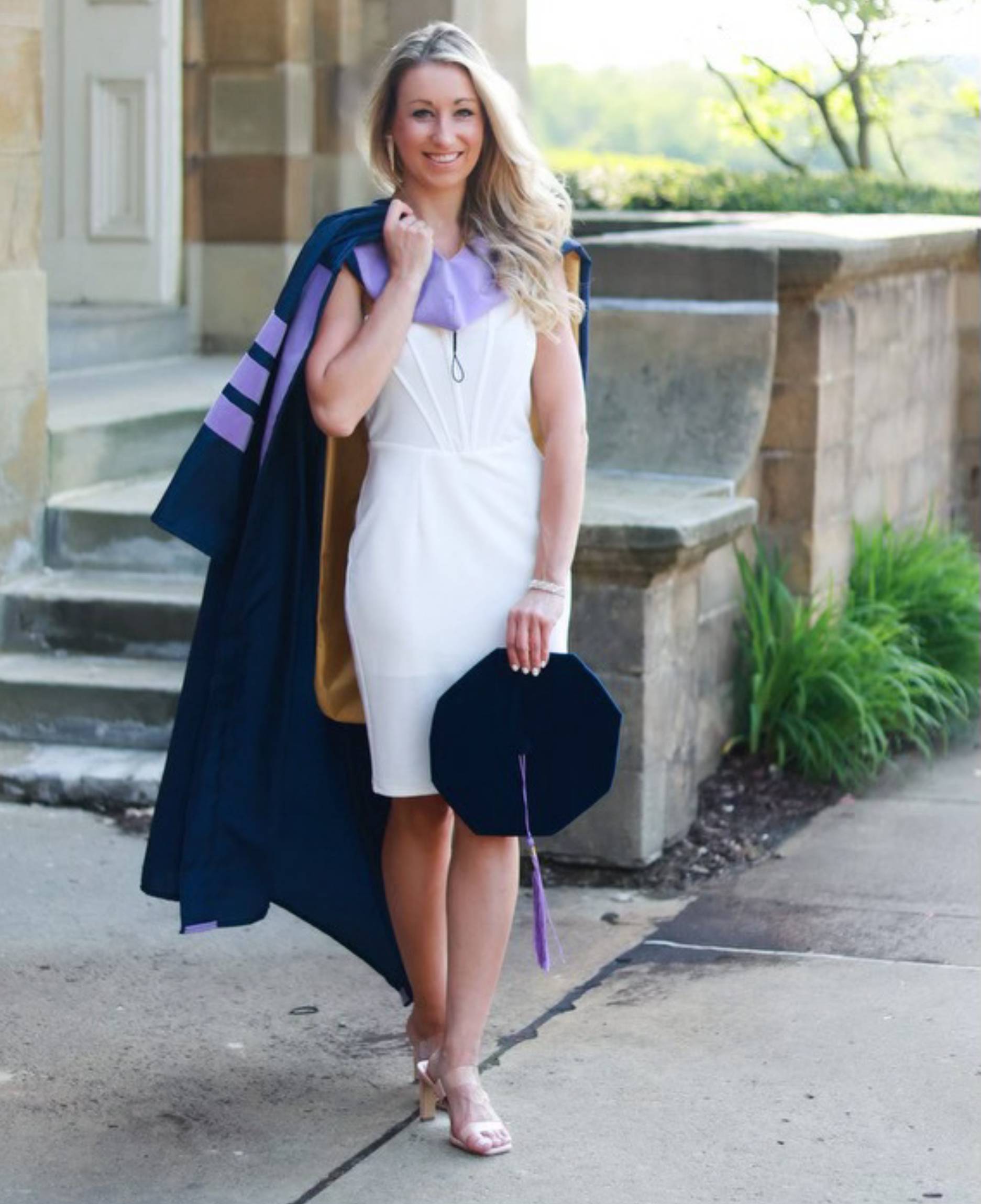 A woman in white dress and graduation cap.