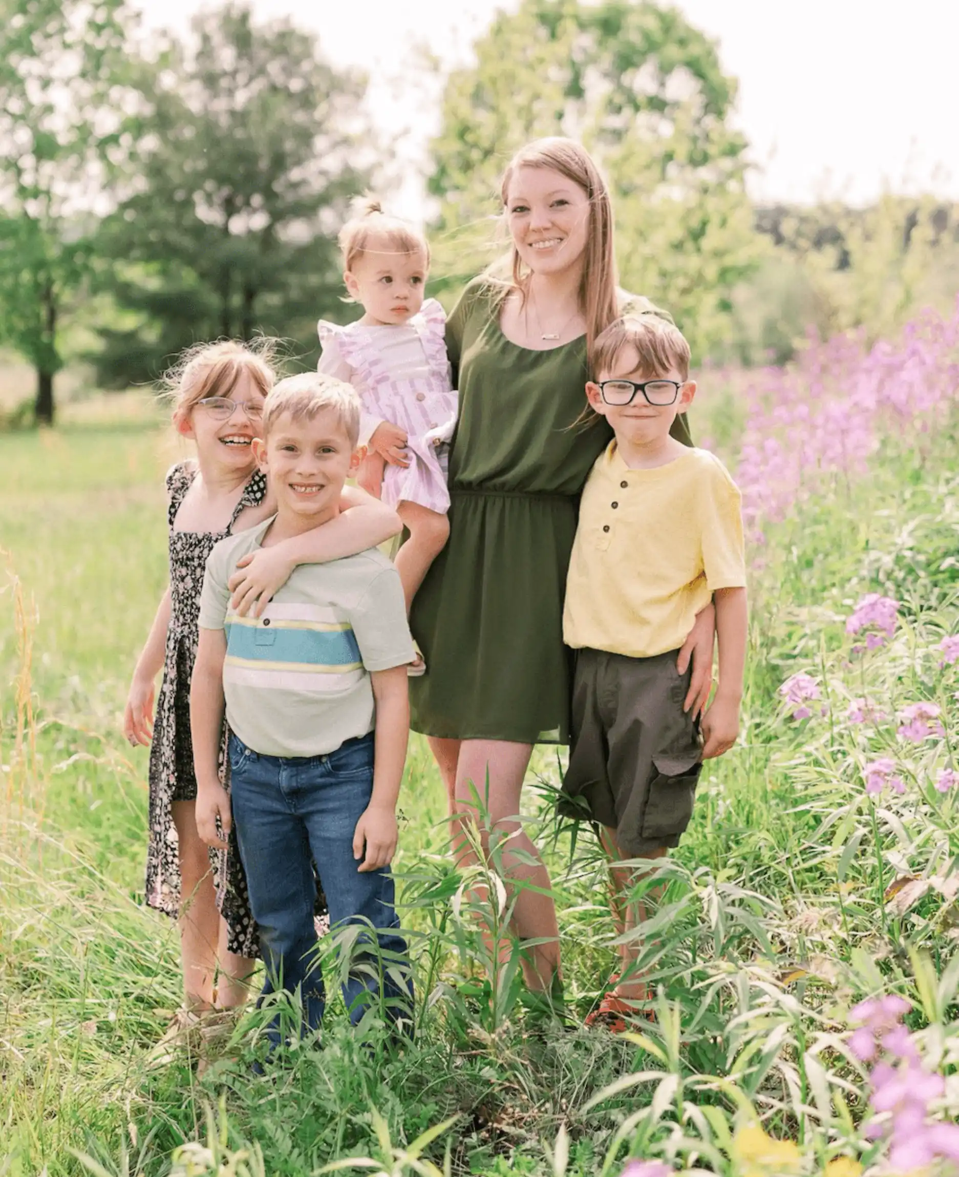 A woman and five children standing in the grass.