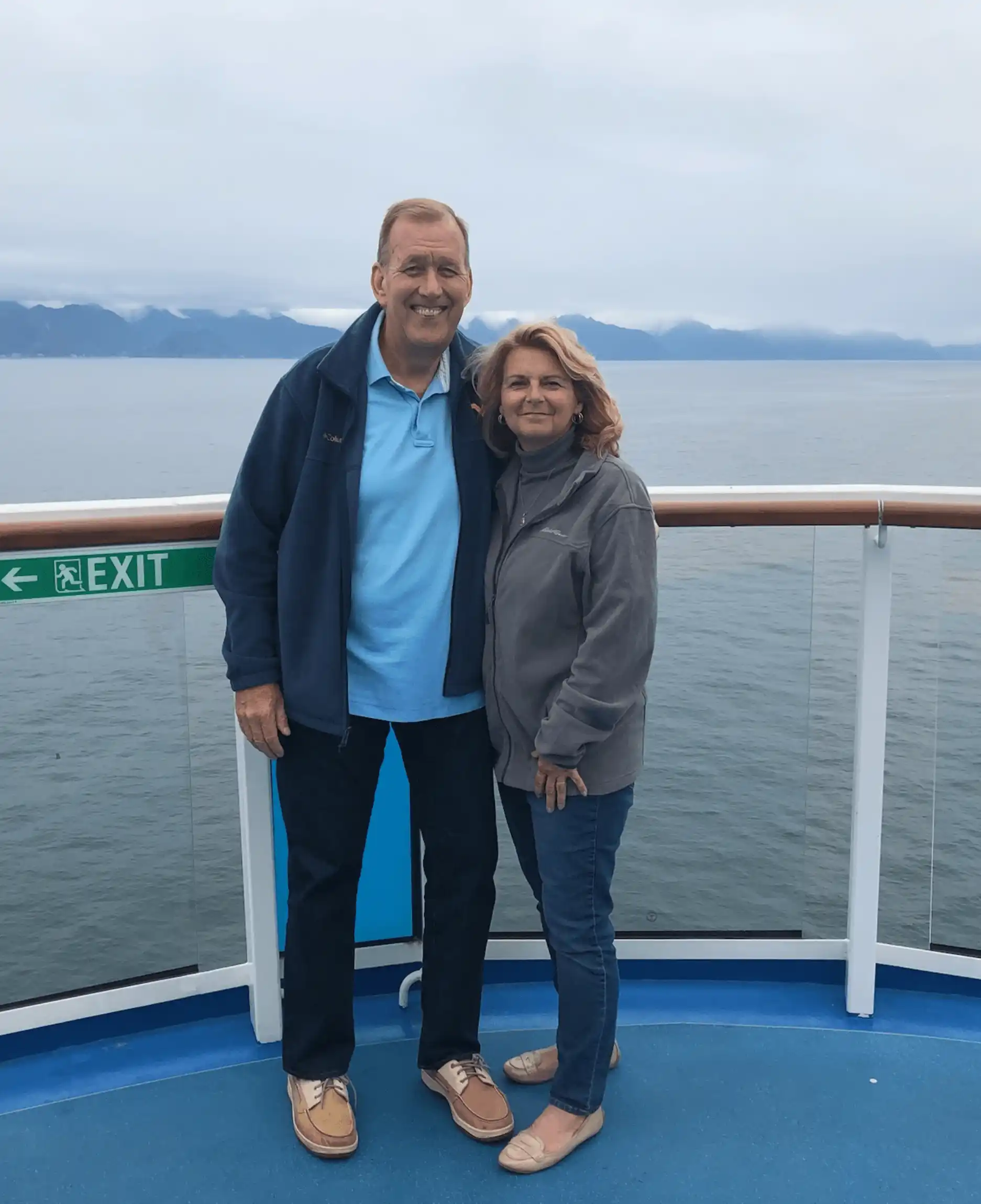 A man and woman standing on the deck of a boat.